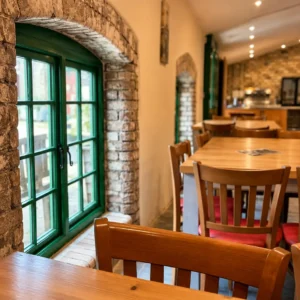 Wooden dining tables next to a traditional green window in the brightly lit main room of Bandpitt Barn